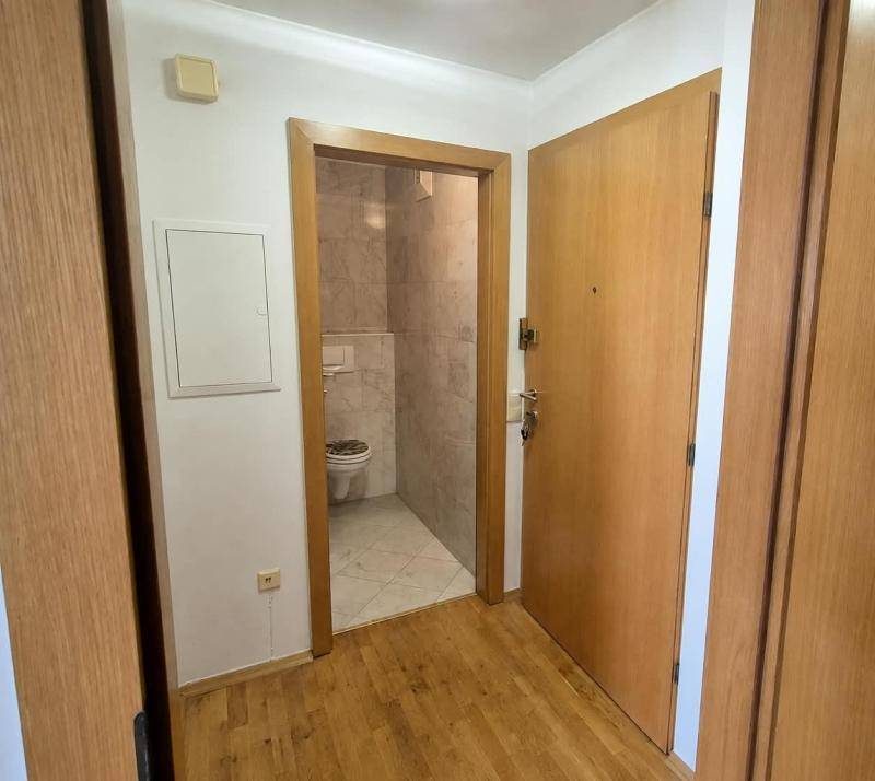Flur mit Holztüren und Zugang zu einem separaten Gäste-WC mit hellen Fliesen.