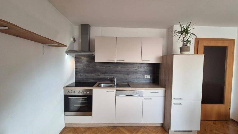 Kompakte Einbauküche mit hellen Schränken, modernen Geräten und praktischer Ausstattung.