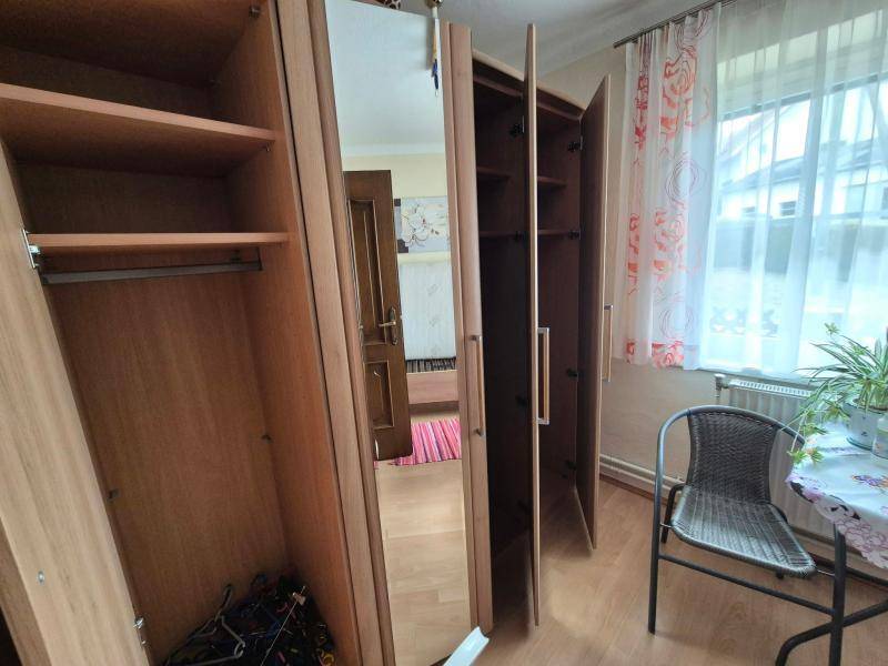 Zimmer mit Laminatboden und Kleiderschränken, bietet Stauraum und Tageslicht durch das Fenster.