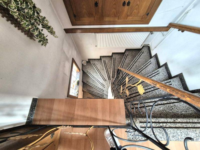 Wendeltreppe mit Terrazzostufen und schmiedeeisernem Geländer, führt in die oberen Stockwerke.