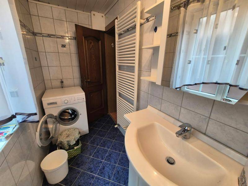 Badezimmer mit blauen Fliesen, Waschbecken, beheiztem Handtuchhalter und Waschmaschine.