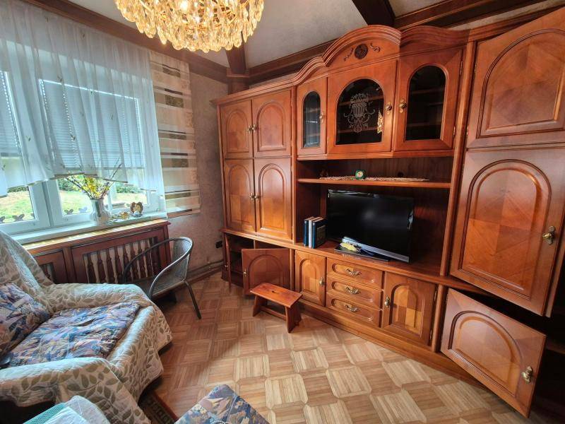 Wohnzimmer mit großer Holzschrankwand, traditionellen Möbeln und Blick nach draußen.
