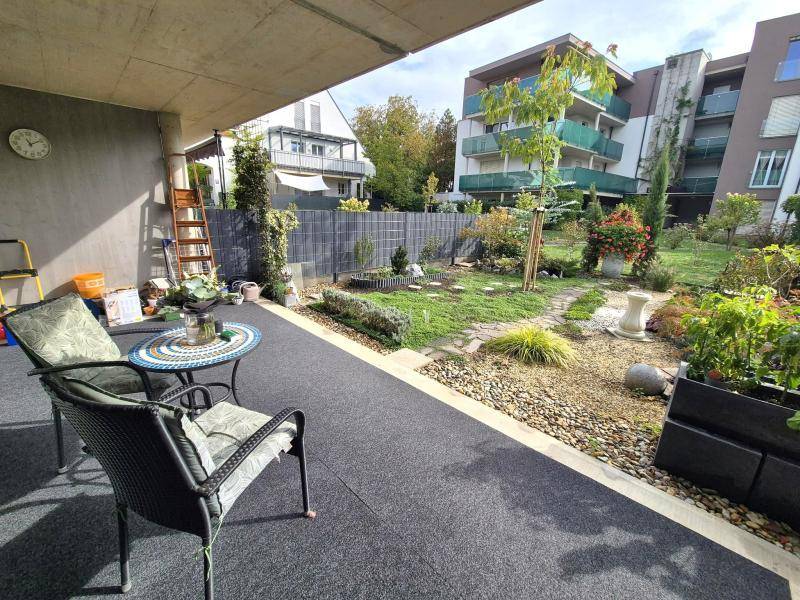 Sonnige Terrasse mit Gartenmöbeln und Blick auf die grüne Umgebung und die Wohnanlage.
