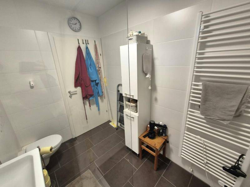 Helles Badezimmer mit großem Handtuchheizkörper, praktischem Stauraum und modernen Fliesen.