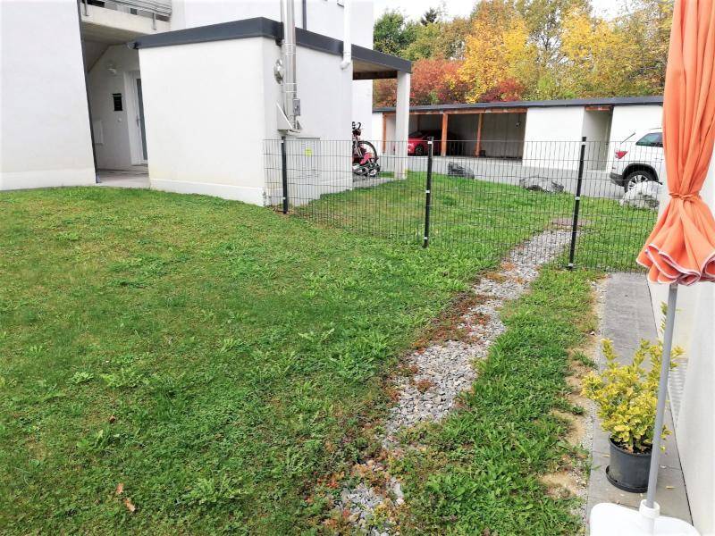 Gartenbereich mit Rasenfläche und Blick auf die Carports im Hintergrund.