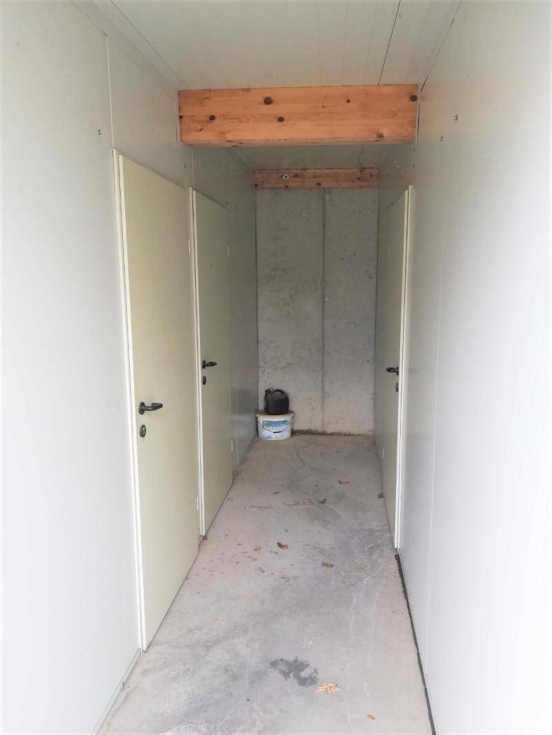 Innenansicht eines Abstellraums mit Betonboden und Holzbalken an der Decke.