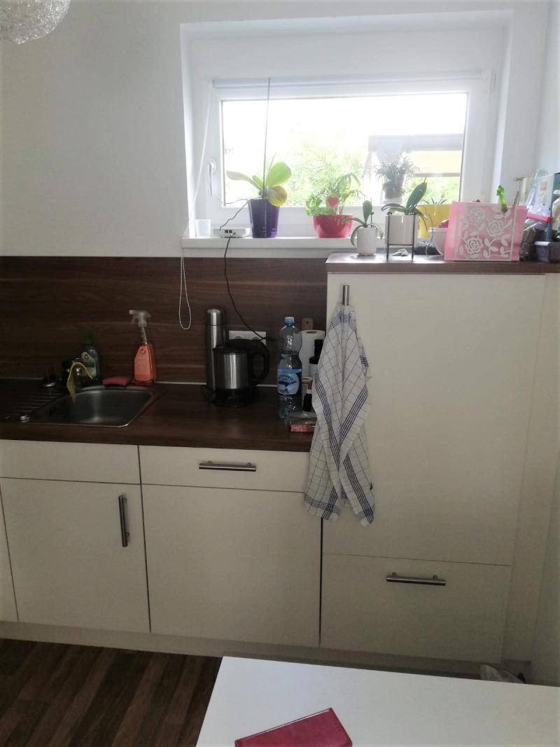 Heller Küchenbereich mit Fenster, weißen Unterschränken und Holzarbeitsplatte.