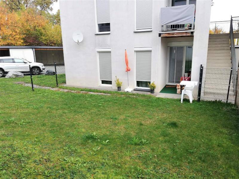 Rückseite des Gebäudes mit kleinem Garten, Rollläden und Balkon im Obergeschoss.