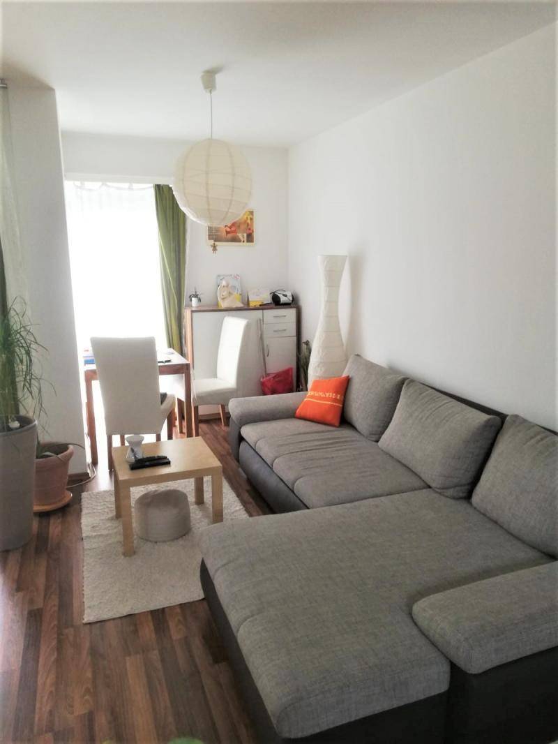 Gemütlicher Wohn- und Essbereich mit Ecksofa, Esstisch und Laminatboden.