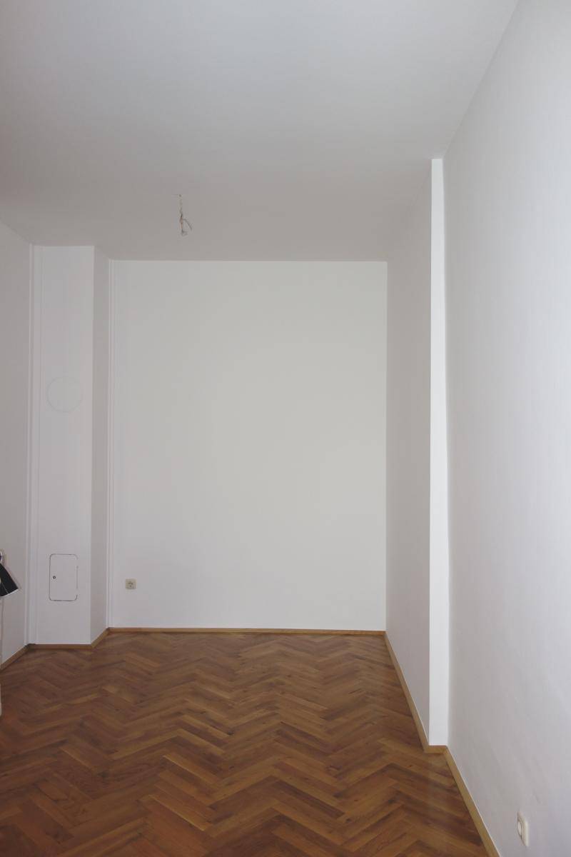 Heller Innenraum mit weißen Wänden und klassischem Fischgrätparkettboden, bereit zur Einrichtung.