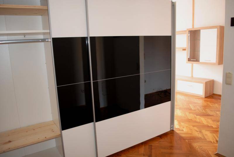 Moderner Schiebetürenschrank mit weißen und schwarzen Paneelen, bietet viel Stauraum.