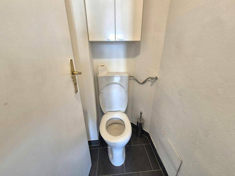 Separates WC mit Toilette, Spülkasten und einem kleinen Wandschrank für zusätzlichen Stauraum.