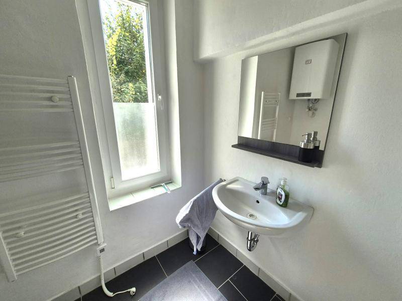 Helles Badezimmer mit modernem Waschbecken, Spiegel und Fenster, das viel Tageslicht hereinlässt.