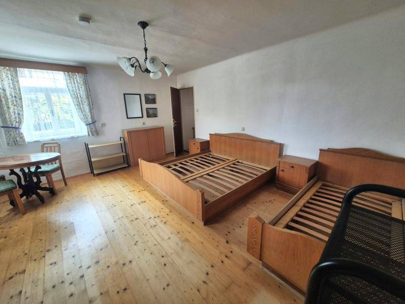 Geräumiges Schlafzimmer mit Holzboden, zwei Bettrahmen und einem Fenster mit Vorhängen.