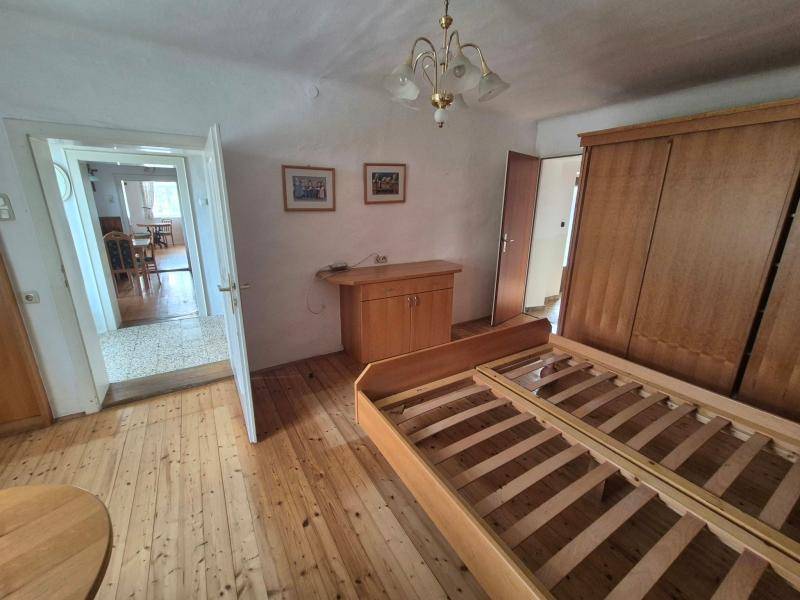 Schlafzimmer mit Holzboden, zwei Bettrahmen und Zugang zu einem weiteren Raum.