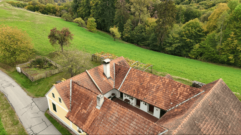 Weitläufige Luftaufnahme des Anwesens mit Innenhof und angrenzenden grünen Hügeln.