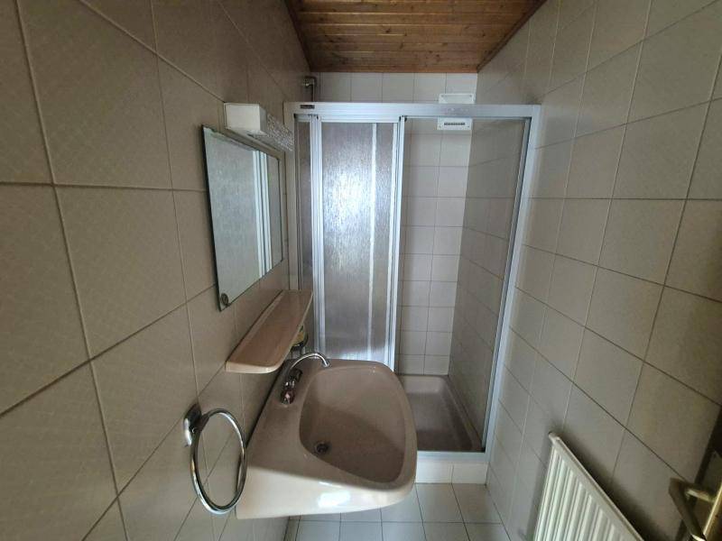 Badezimmer mit Duschkabine, Waschbecken und Fliesenboden, in hellem Farbton gehalten.