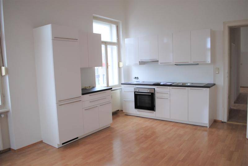 Geräumige, helle Küche mit weißen Schränken, dunkler Arbeitsplatte und Laminatboden.