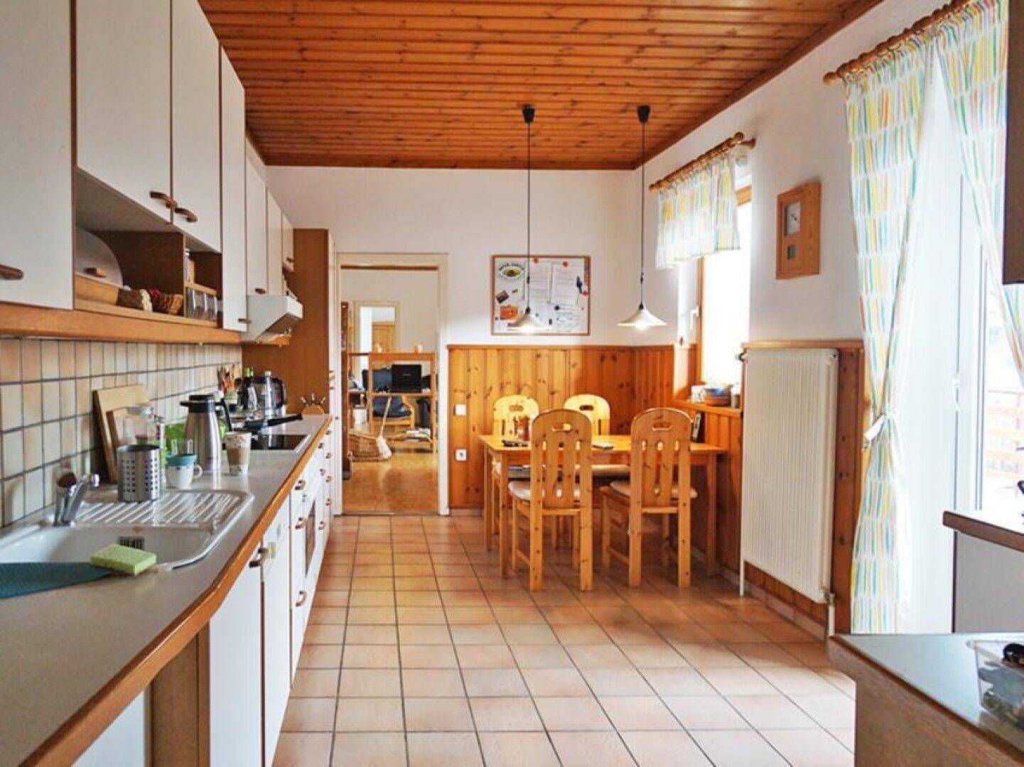 Gemütliche Wohnküche mit Holztäfelung, Essbereich und Zugang zu einem Außenbereich.