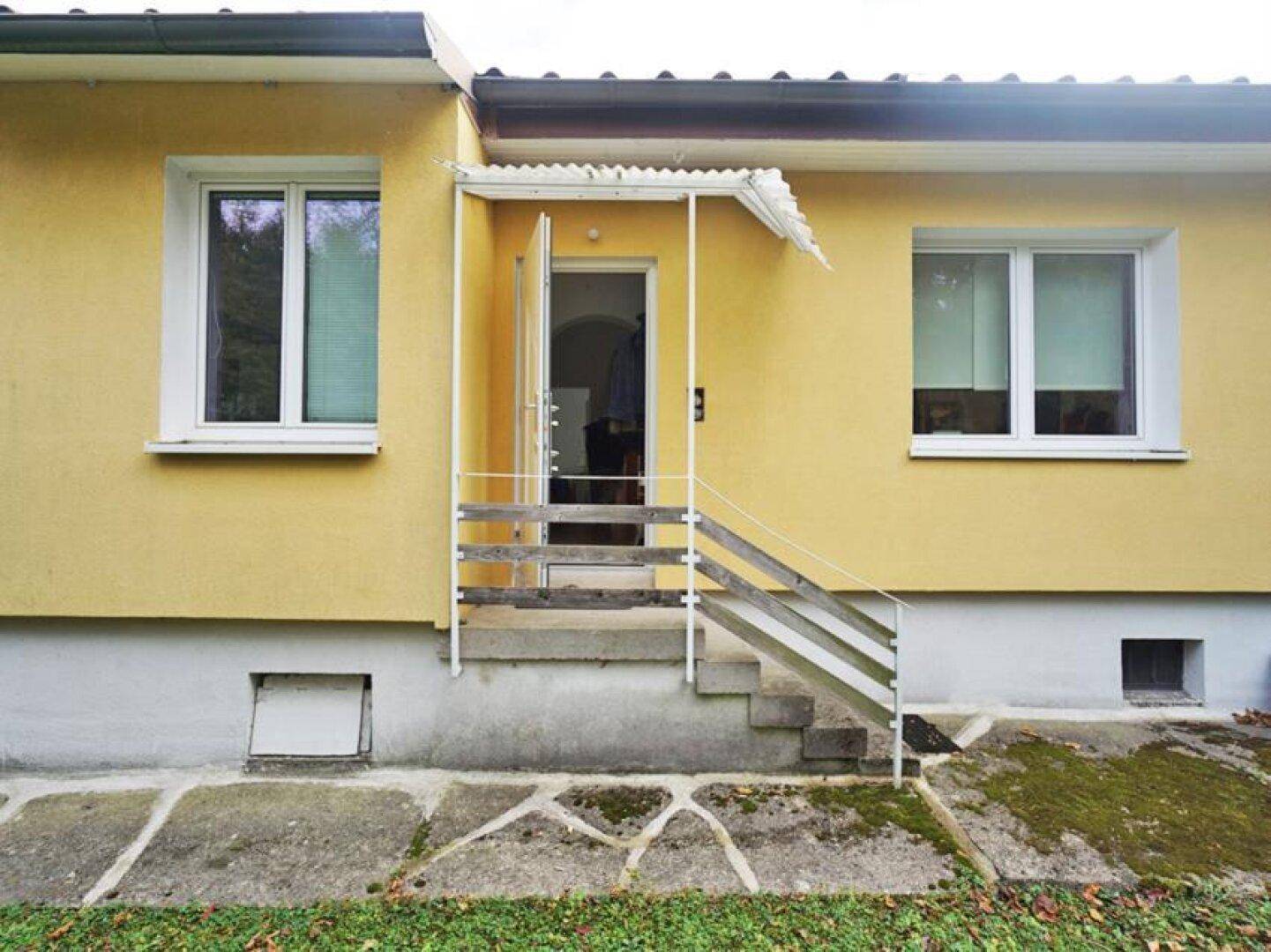 Eingangsbereich des Hauses mit kleiner Überdachung und einer Treppe zum Garten.