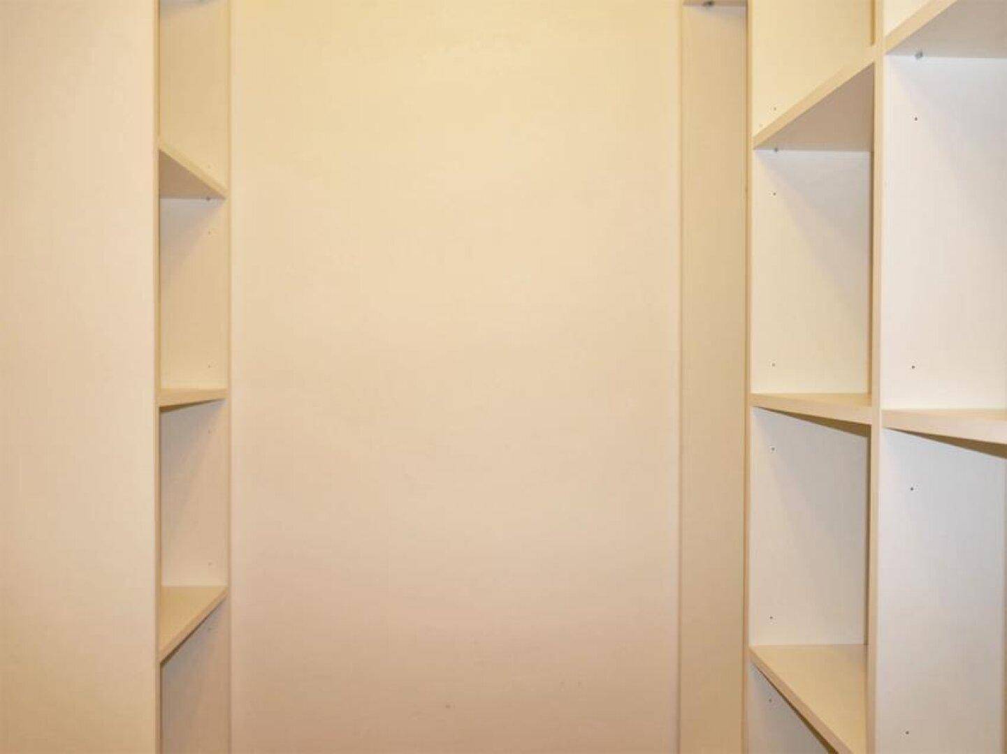 Heller Raum mit praktischen Einbauregalen an beiden Seiten, ideal als Abstellraum oder begehbarer Kleiderschrank.