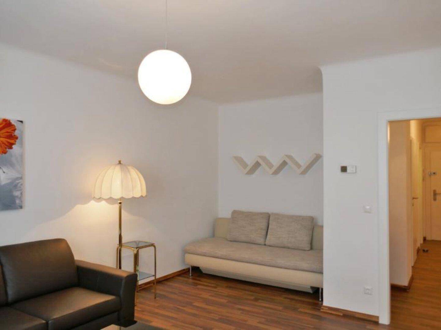 Gemütliches Wohnzimmer mit bequemen Sofas, Holzboden und einer modernen Deckenleuchte.