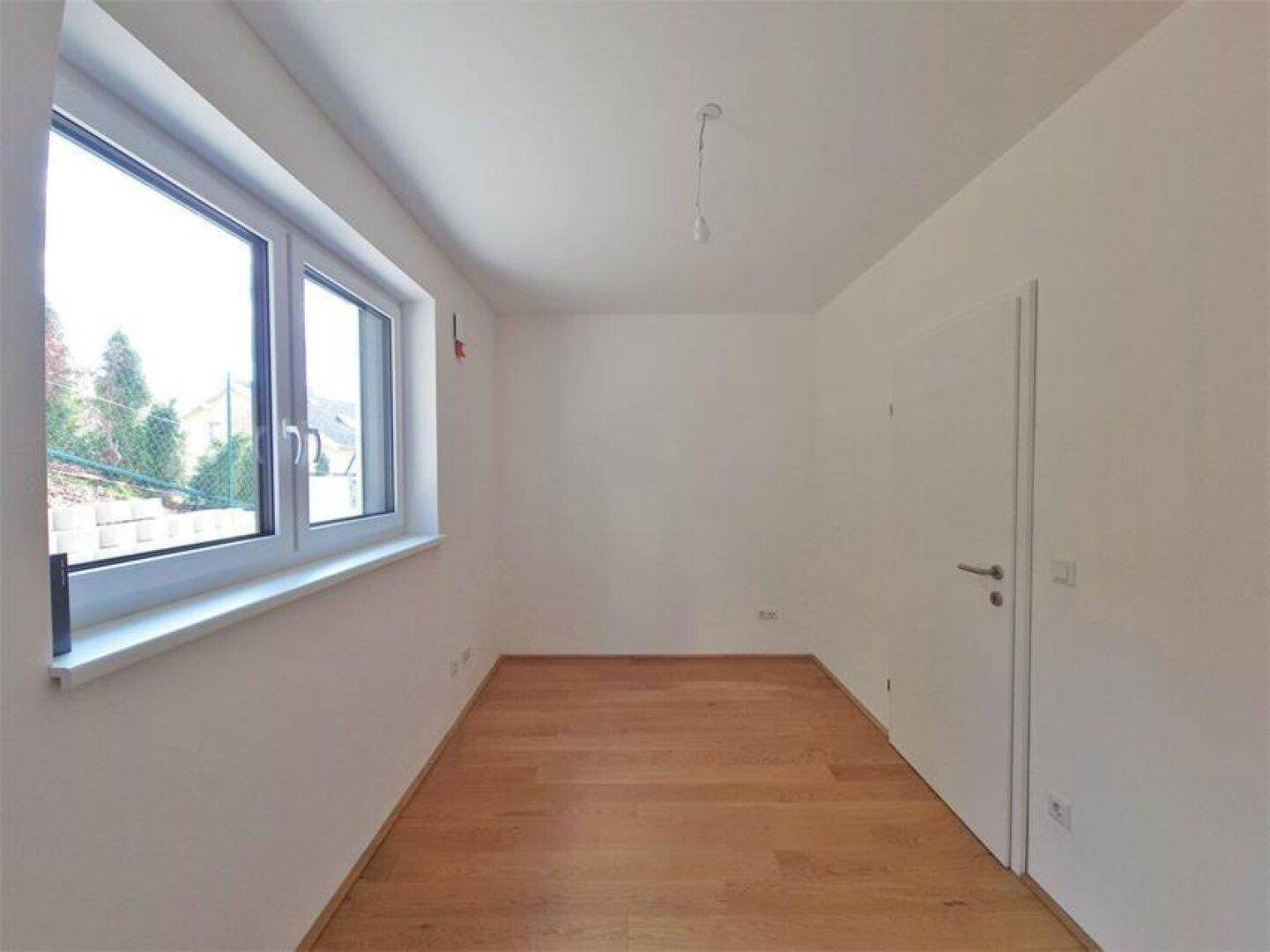 Helles, unmöbliertes Zimmer mit Holzboden und Fenster, geeignet als Schlaf- oder Arbeitszimmer.