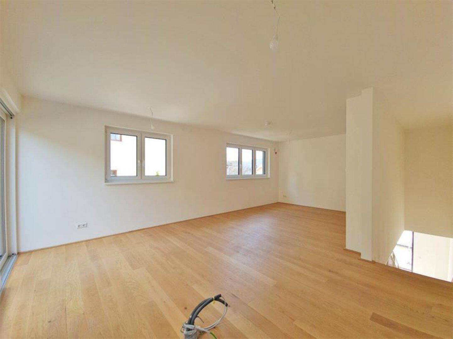 Heller, leerer Raum mit Holzboden und mehreren Fenstern, bereit zur Einrichtung.