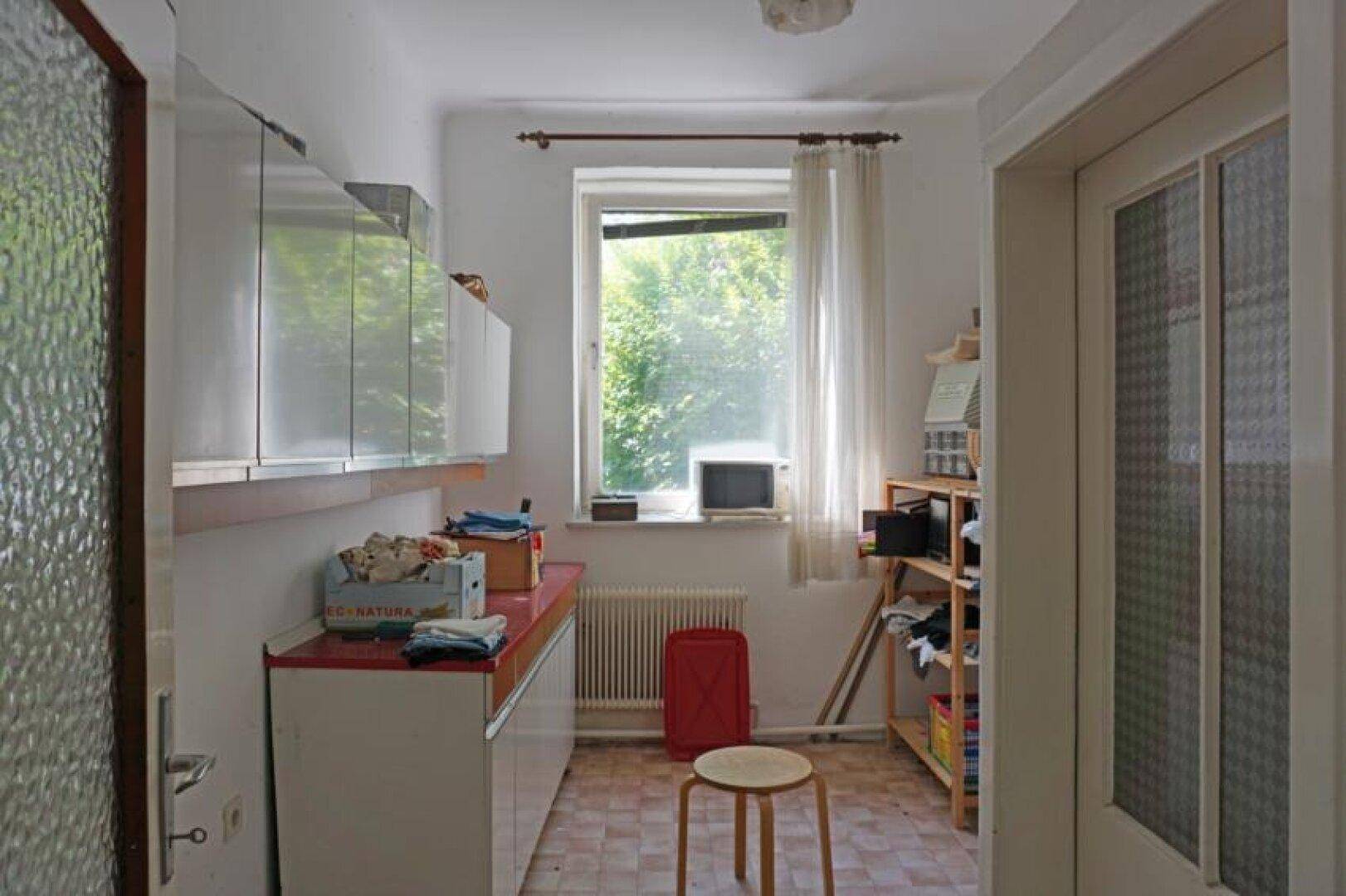 Praktischer Hauswirtschaftsraum mit Regalen, Schränken und Fenster, ideal für zusätzlichen Stauraum.