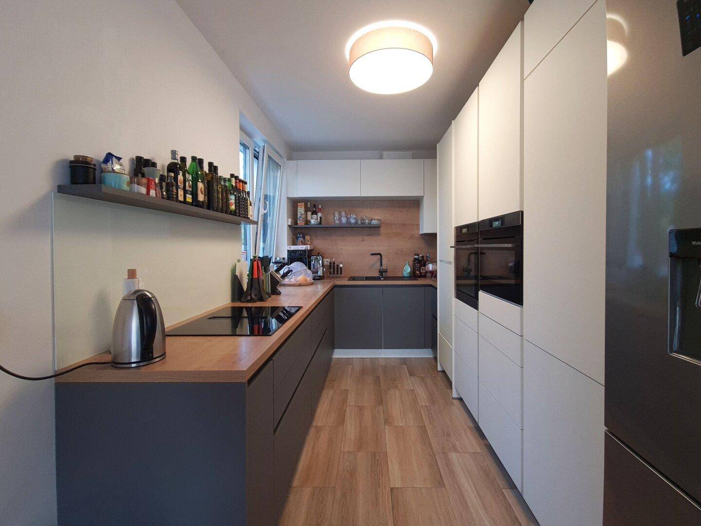 Moderne Küche mit Holz-Arbeitsplatte, integrierten Geräten und viel Stauraum.
