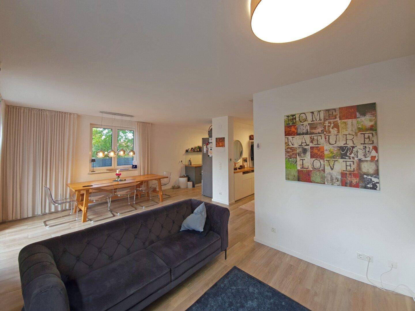 Offener Wohn- und Essbereich mit modernem Sofa und Blick in die Küche.