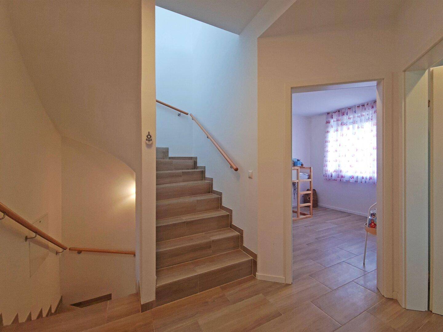 Treppenhaus mit Holzgeländer und Zugang zu einem weiteren Zimmer.