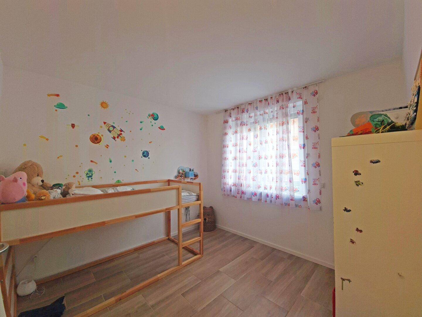 Kinderzimmer mit Etagenbett, verspielter Wanddekoration und hellem Boden.