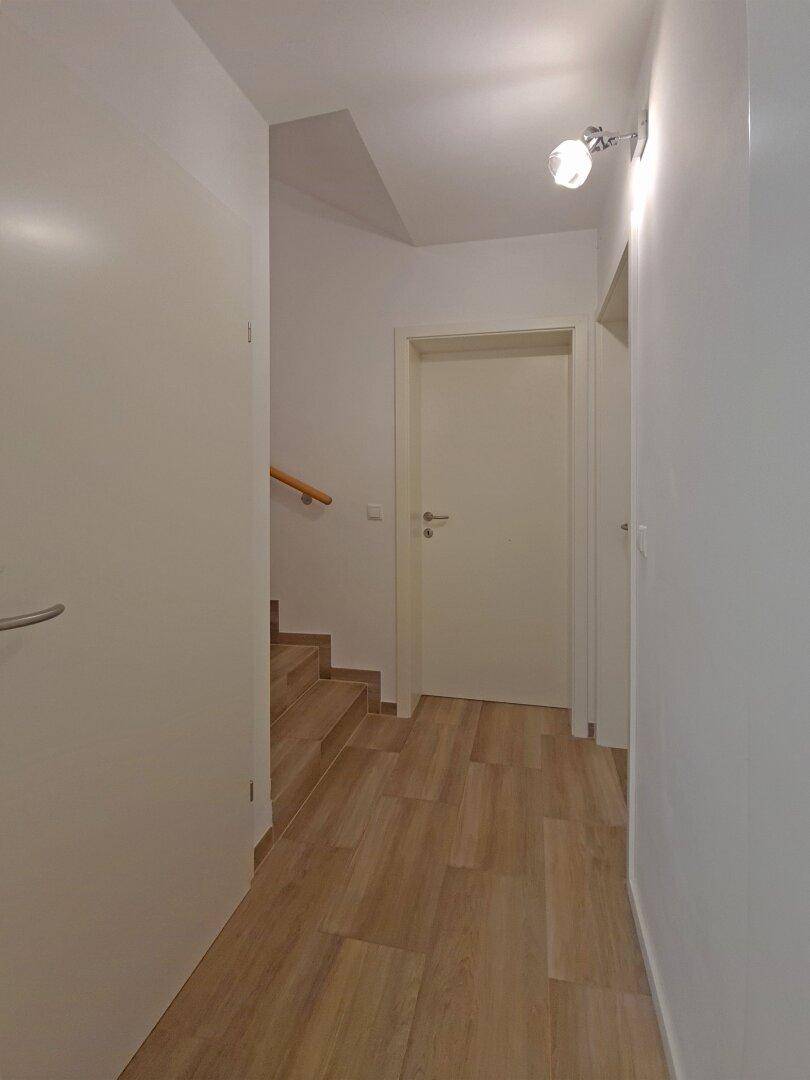 Heller Flur mit Zugang zu mehreren Zimmern und dem Treppenhaus.
