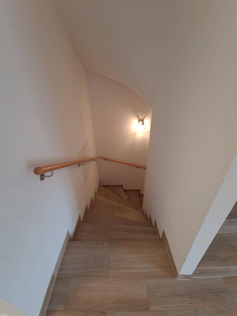 Wendeltreppe mit Holzgeländer, die die verschiedenen Ebenen des Hauses verbindet.
