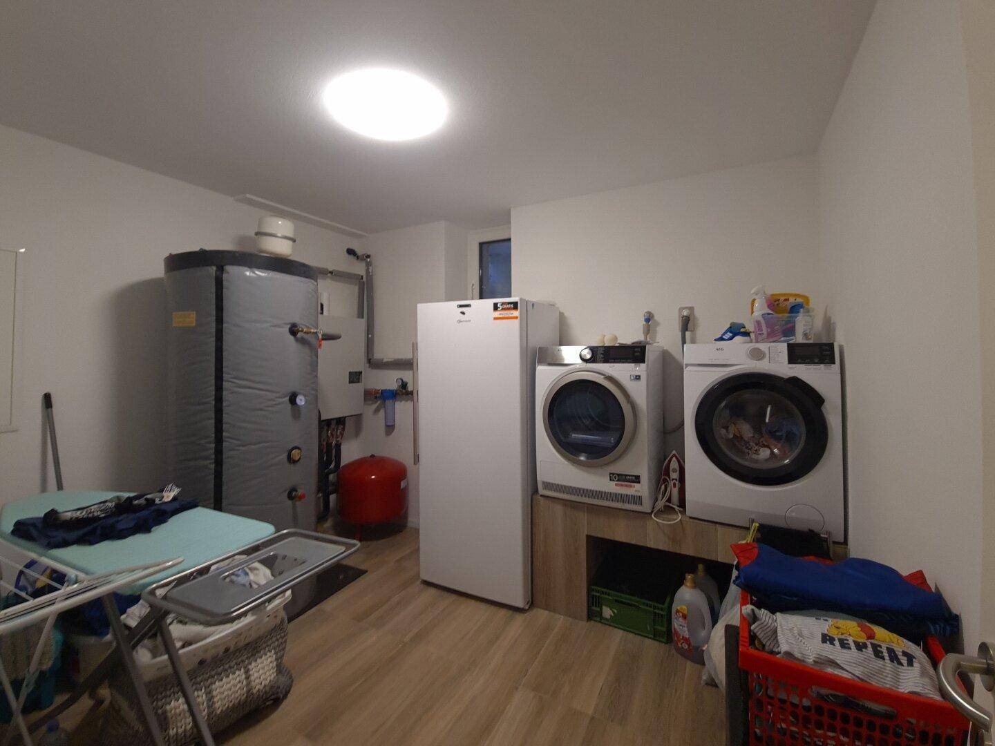 Praktischer Hauswirtschaftsraum mit Waschmaschine, Trockner und Warmwasserspeicher.