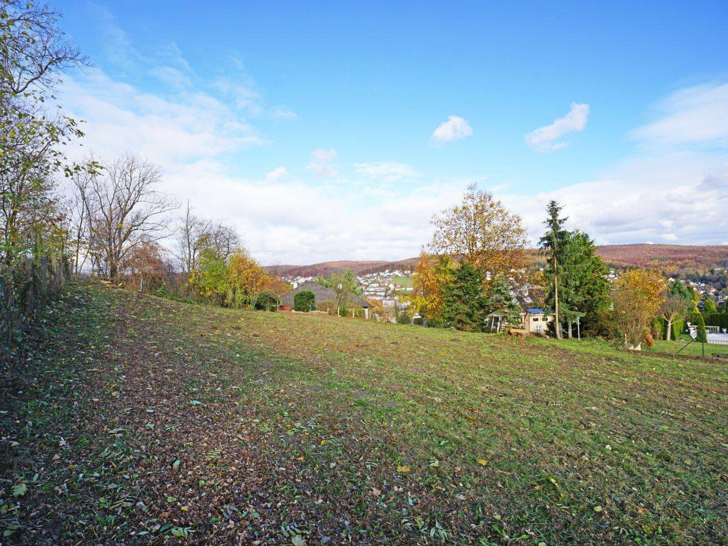 Großes, offenes Grundstück mit weitem Blick über die umliegende Landschaft und eine Siedlung.