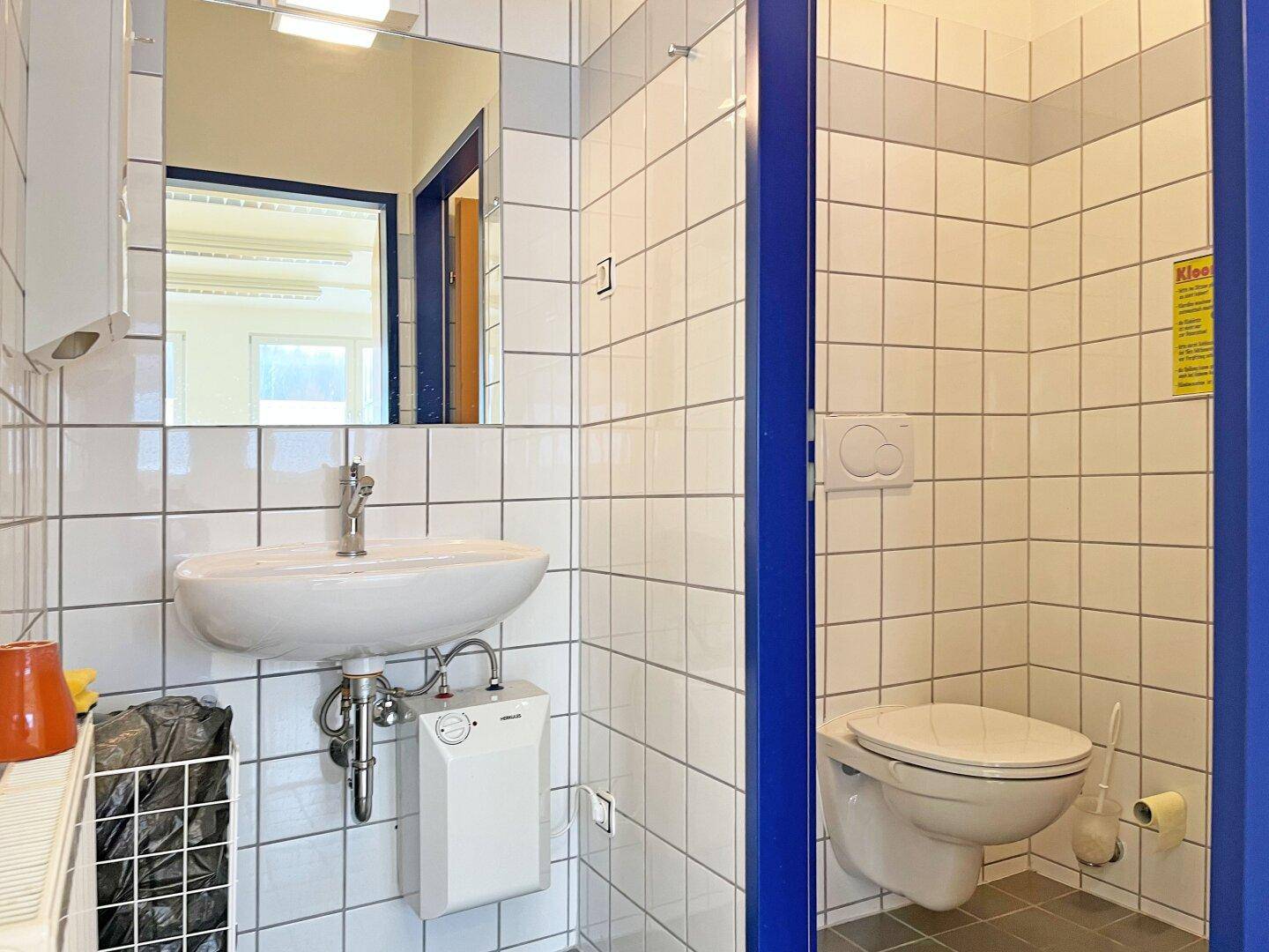 Sauberes Badezimmer mit weiß gefliesten Wänden, Waschbecken und Wand-WC, funktional gestaltet.