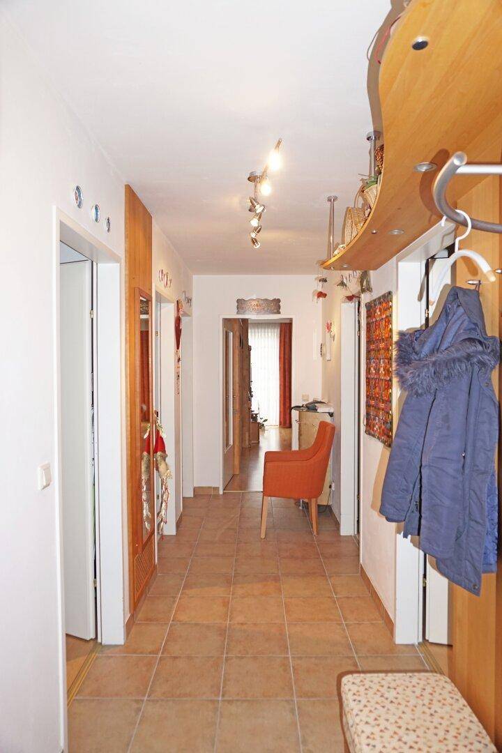 Heller Flur mit Fliesenboden, Garderobe und Zugang zu weiteren Räumen.