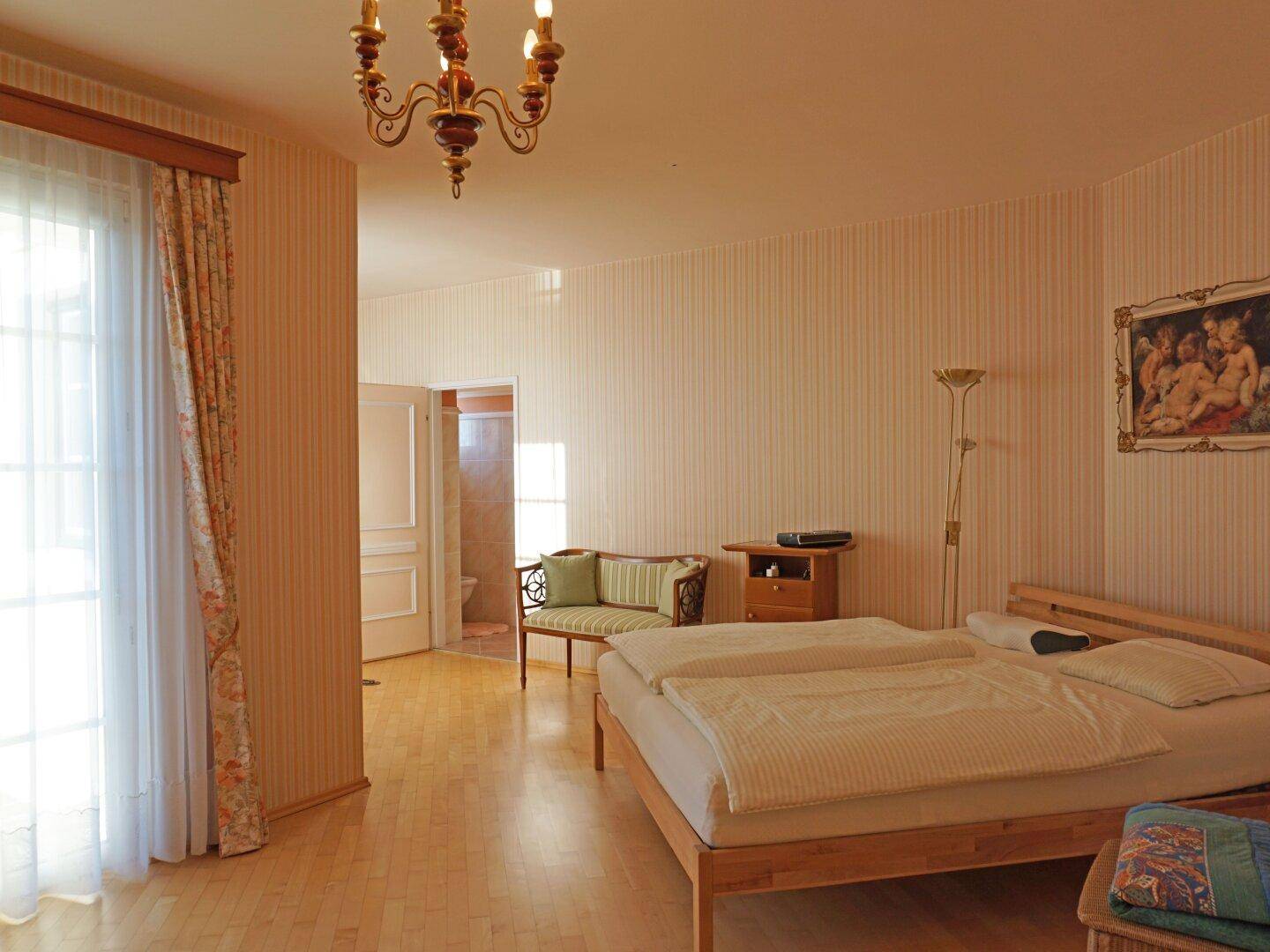 Geräumiges Schlafzimmer mit Holzboden, Doppelbett und Zugang zu einem Außenbereich.
