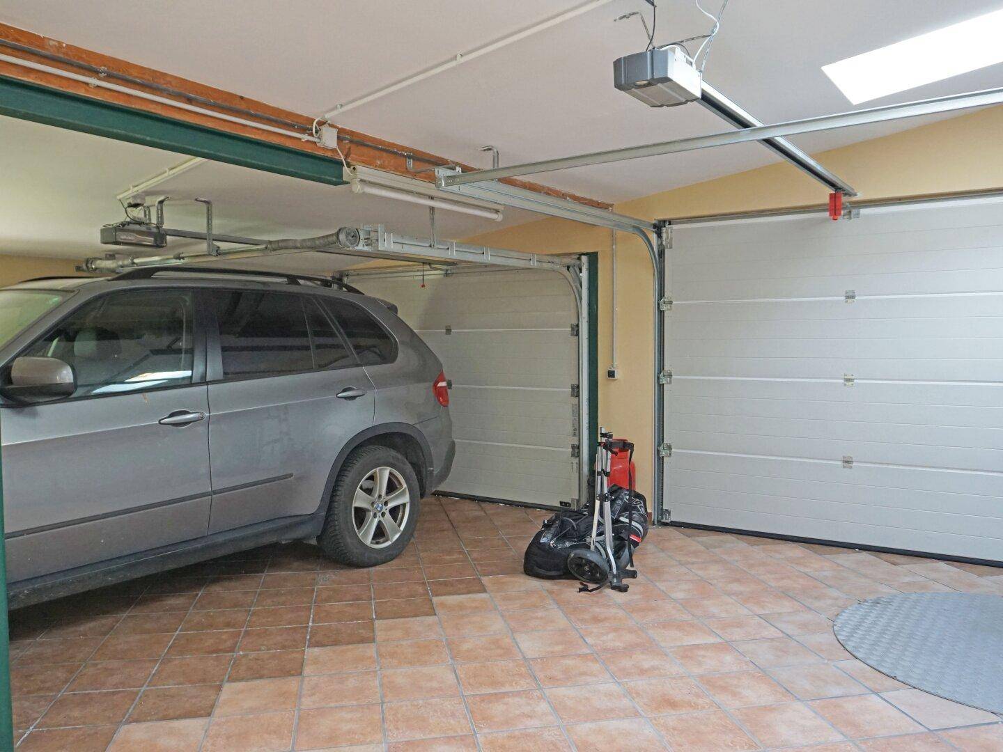 Geräumige Garage mit Fliesenboden und automatischen Toren für mehrere Fahrzeuge.