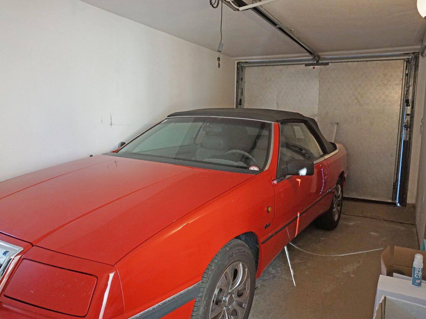 Einzelgarage mit rotem Oldtimer und automatischem Garagentor.