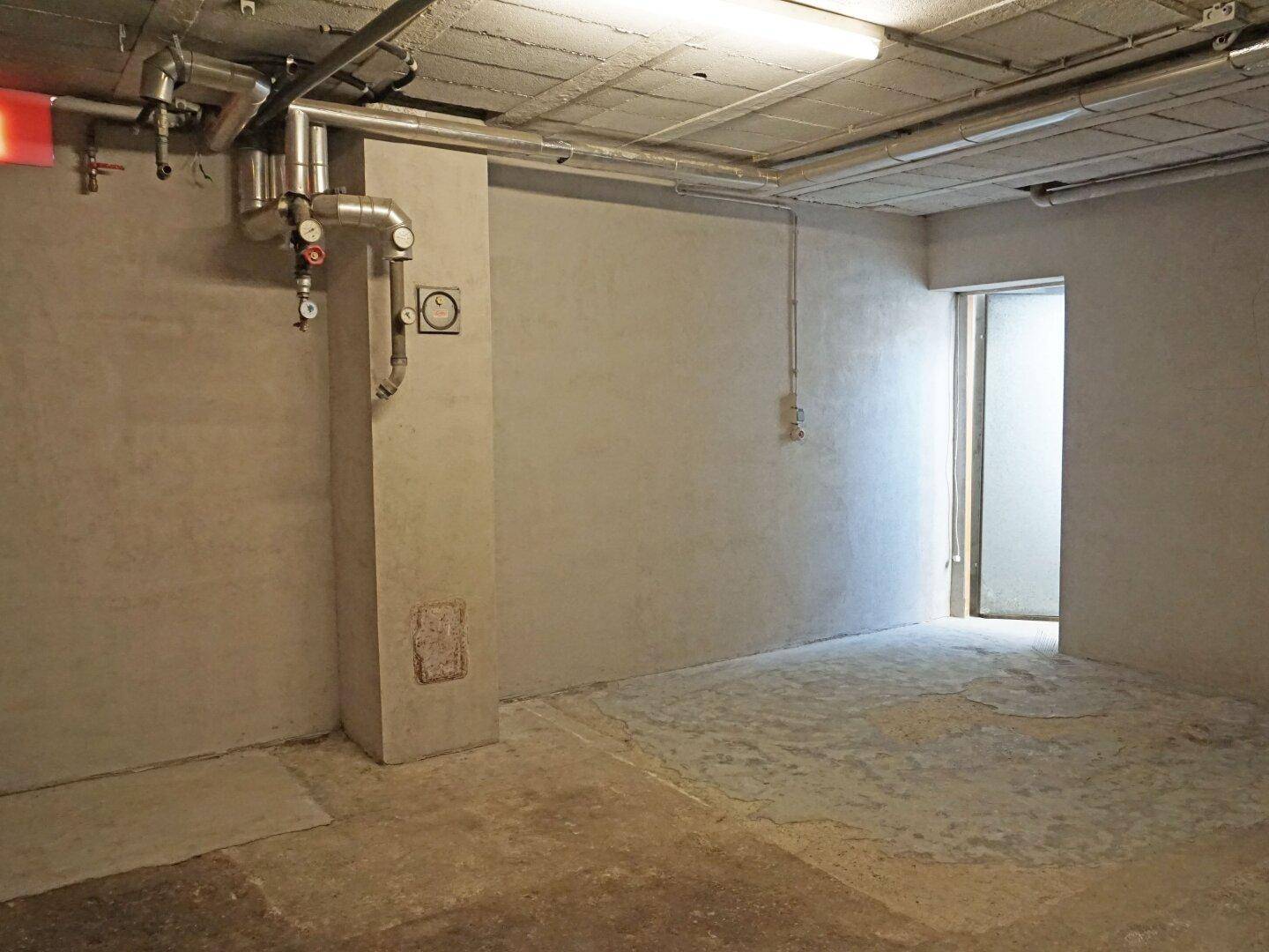 Unfertiger Kellerraum mit Betonboden und sichtbaren Installationen.