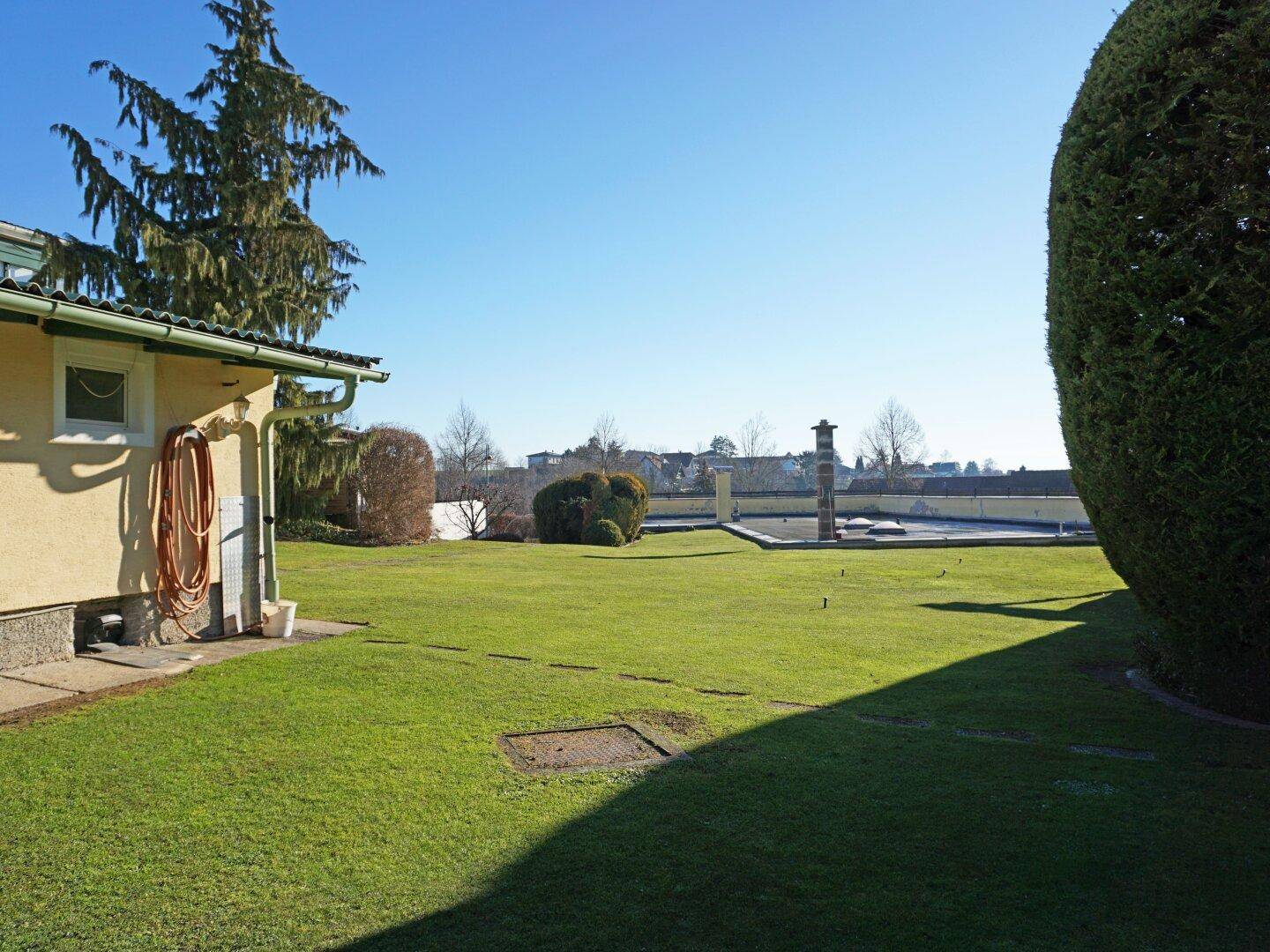 Großer, gepflegter Rasengarten mit Hecken und Blick auf die Umgebung.
