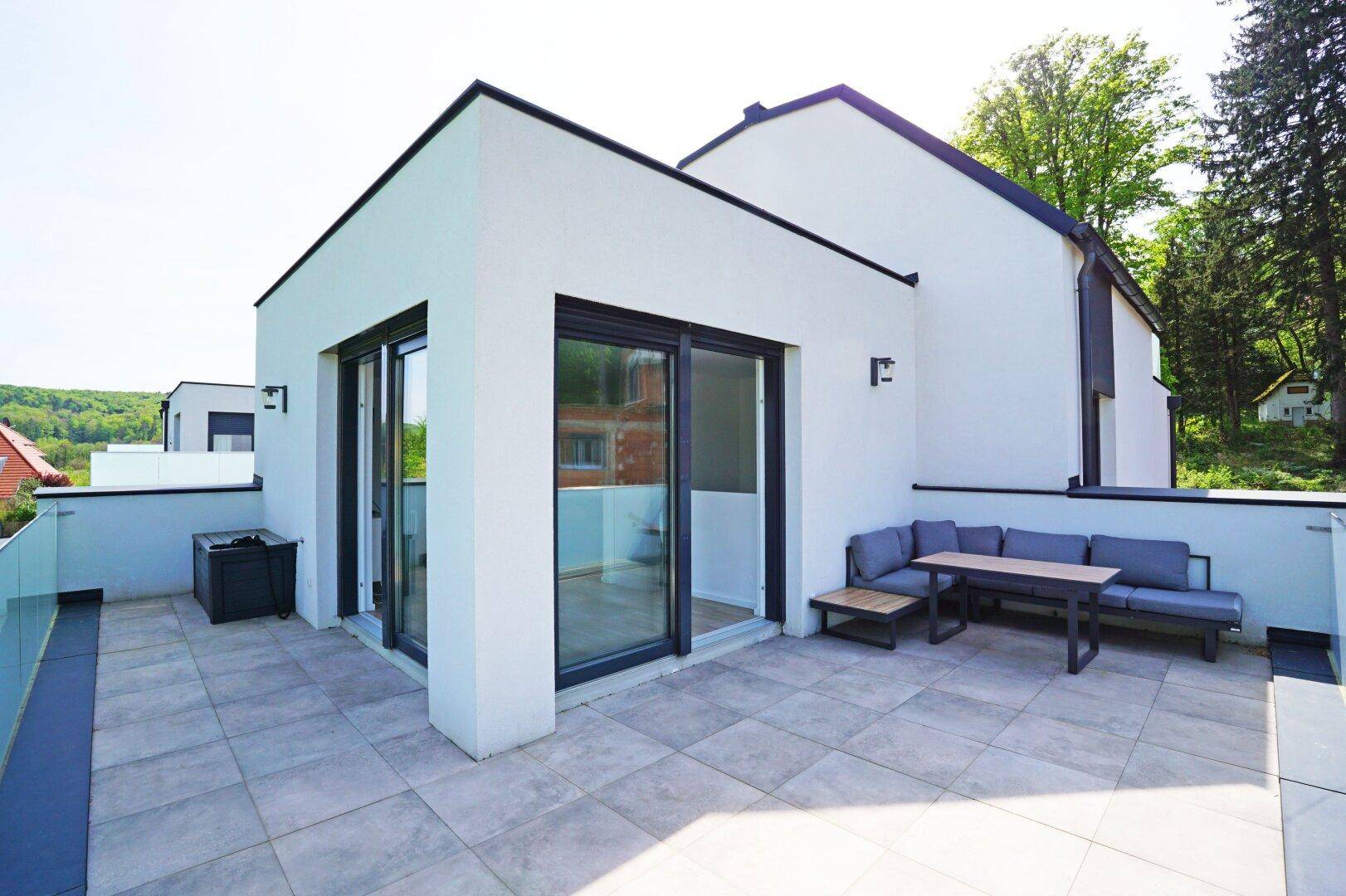Geräumige Dachterrasse mit bequemen Lounge-Möbeln und großen Glasschiebetüren zum Innenbereich.