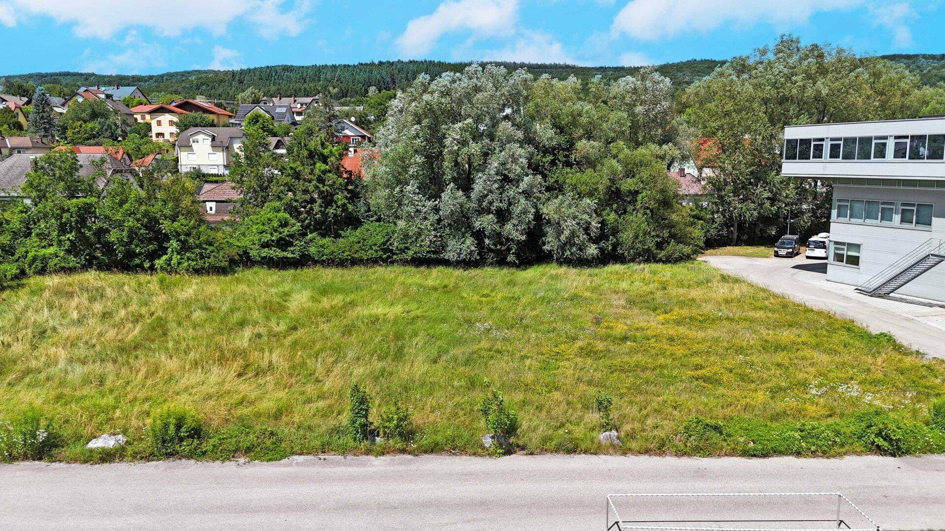 Großes, sonniges Grundstück neben einem modernen Geschäftsgebäude mit Blick auf die umliegende Landschaft.