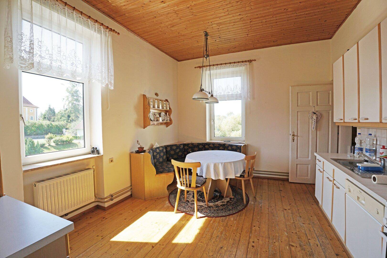 Helle Küche mit Holzboden, Essbereich und Holzdecke.