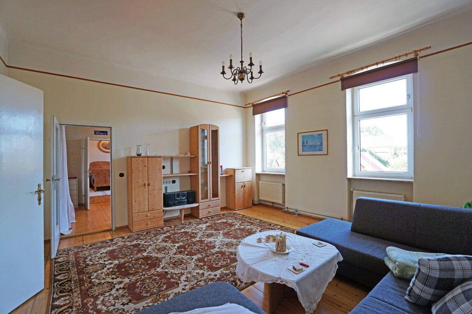 Gemütliches Wohnzimmer mit Holzboden, großem Teppich und bequemer Sofalandschaft.