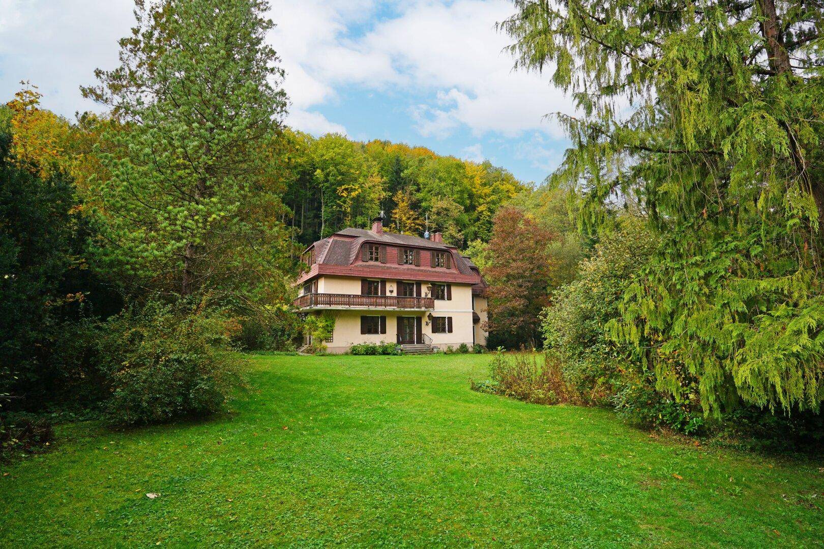 Das Haus liegt idyllisch inmitten eines großen Gartens, umgeben von Wald und Natur.