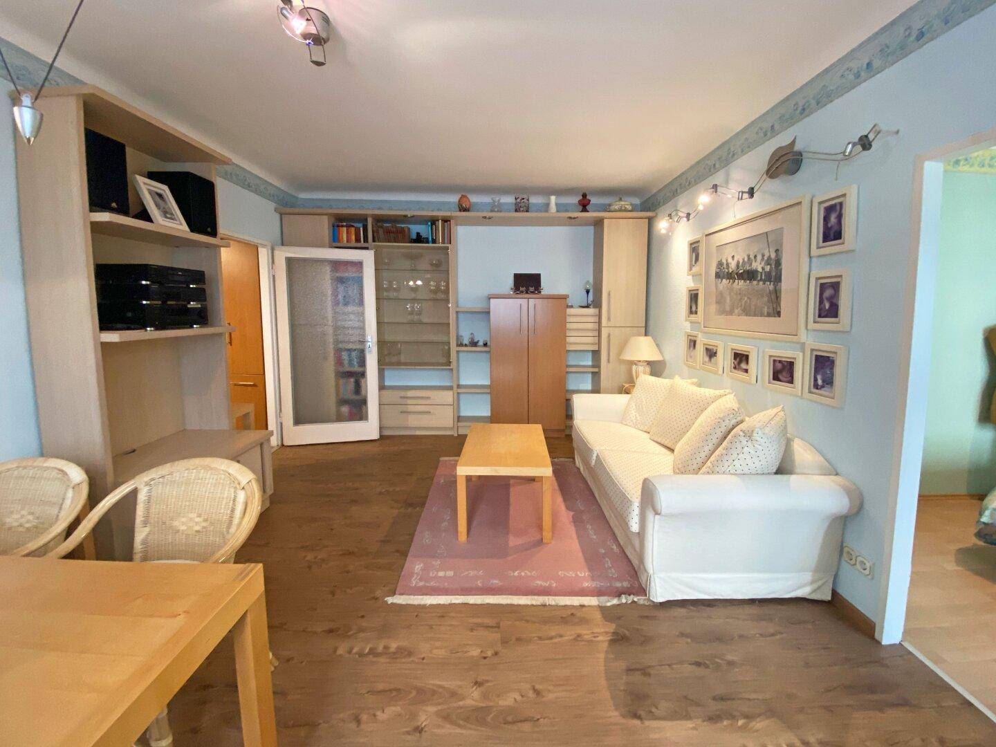 Geräumiger Wohn-Essbereich mit Holzfußboden, integrierten Regalen und einem bequemen Sofa.